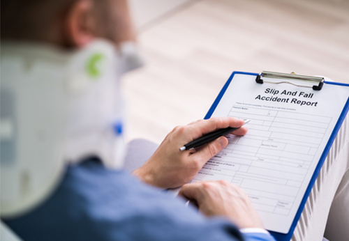 Close-up of an injured person wearing a neck brace, filling out a Slip And Fall Accident Report on a clipboard.