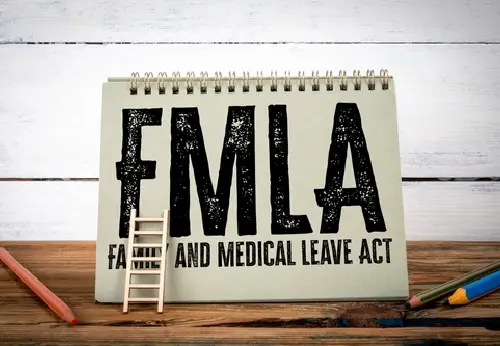 FMLA family and medical leave act concept on spiral notebook with ladder and pencils